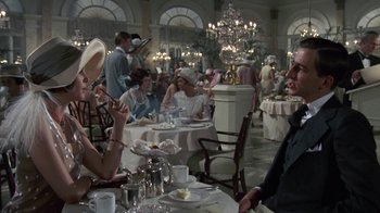 Movie still from “The Great Gatsby” (1974), directed by Jack Clayton – A group of people sitting at tables in a restaurant; Medium shot, Over the shoulder angle