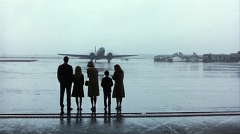 Movie still from “The Great Santini” (1979), directed by Lewis John Carlino – A group of people standing in front of an airplane on a runway; Wide shot, Low angle