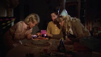 Movie still from “The Great Santini” (1979), directed by Lewis John Carlino – A group of people sitting at a table with a birthday cake; Medium shot, High angle