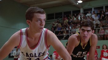 Movie still from “The Great Santini” (1979), directed by Lewis John Carlino – A man in a white and red basketball uniform is in front of a crowd of people; Close Up shot, Low angle