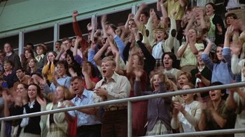 Movie still from “The Great Santini” (1979), directed by Lewis John Carlino – A group of people in the stands with their hands in the air; Wide shot, High angle