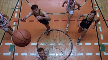 Movie still from “The Great Santini” (1979), directed by Lewis John Carlino – A group of young men playing a game of basketball on an indoor court; Wide shot, Overhead angle