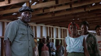 Movie still from “The Great Santini” (1979), directed by Lewis John Carlino – A group of people standing in front of a wooden structure; Medium shot, Low angle