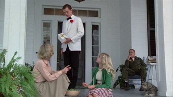 Movie still from “The Great Santini” (1979), directed by Lewis John Carlino – A man in a white jacket standing next to two women; Wide shot, Low angle