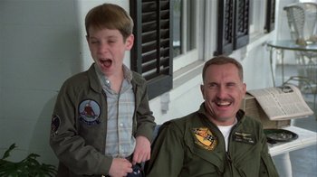 Movie still from “The Great Santini” (1979), directed by Lewis John Carlino – A man and a boy are smiling for the camera; Medium shot, Low angle
