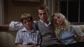 Movie still from “The Great Santini” (1979), directed by Lewis John Carlino – A man and two young boys sitting next to each other on a couch; Medium shot, Low angle