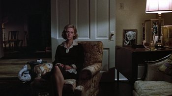Movie still from “The Great Santini” (1979), directed by Lewis John Carlino – A woman sitting on a chair in a living room; Wide shot, High angle