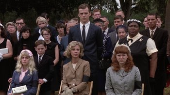 Movie still from “The Great Santini” (1979), directed by Lewis John Carlino – A group of people in suits and ties sitting and standing in front of each other; Medium shot, Low angle