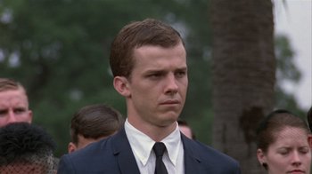 Movie still from “The Great Santini” (1979), directed by Lewis John Carlino – A man in a suit and tie standing in front of a tree; Close Up shot, Low angle