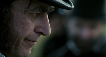 Movie still from “The Greatest Game Ever Played” (2005), directed by Bill Paxton – An older man wearing a black hat looking to his left; Extreme Close Up shot, Over the shoulder angle