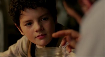 Movie still from “The Greatest Game Ever Played” (2005), directed by Bill Paxton – A young boy is looking at a jar of food; Close Up shot, Over the shoulder angle