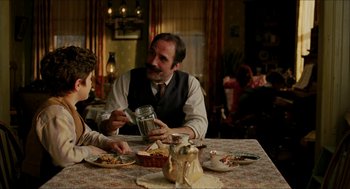 Movie still from “The Greatest Game Ever Played” (2005), directed by Bill Paxton – Two people sitting at a table with food; Medium shot, Over the shoulder angle