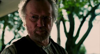 Movie still from “The Greatest Game Ever Played” (2005), directed by Bill Paxton – An older man with glasses and a beard; Close Up shot, Over the shoulder angle
