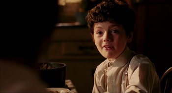 Movie still from “The Greatest Game Ever Played” (2005), directed by Bill Paxton – A young boy sitting at a table with a bowl of food; Close Up shot, Over the shoulder angle