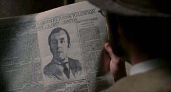 Movie still from “The Greatest Game Ever Played” (2005), directed by Bill Paxton – A person reading a newspaper with a drawing of a man; Close Up shot, Low angle
