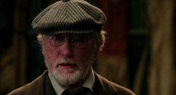 Movie still from “The Greatest Game Ever Played” (2005), directed by Bill Paxton – An older man wearing glasses and a hat; Close Up shot, Over the shoulder angle