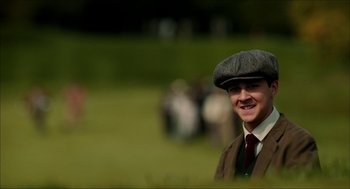Movie still from “The Greatest Game Ever Played” (2005), directed by Bill Paxton – A man wearing a flat cap and a suit; Medium shot, Low angle