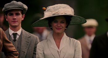 Movie still from “The Greatest Game Ever Played” (2005), directed by Bill Paxton – A woman wearing a hat with a flower on it's brim; Close Up shot, Over the shoulder angle