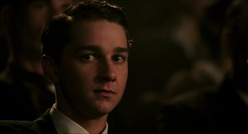 Movie still from “The Greatest Game Ever Played” (2005), directed by Bill Paxton – A man in a white dress shirt is looking at the camera; Close Up shot, Over the shoulder angle