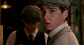 Movie still from “The Greatest Game Ever Played” (2005), directed by Bill Paxton – A young man wearing a hat and a tie; Close Up shot, Over the shoulder angle