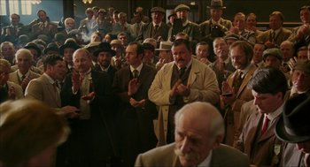 Movie still from “The Greatest Game Ever Played” (2005), directed by Bill Paxton – A group of men standing in a room clapping; Wide shot, High angle