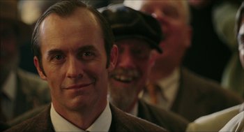 Movie still from “The Greatest Game Ever Played” (2005), directed by Bill Paxton – A person wearing a suit and hat; Close Up shot, Over the shoulder angle