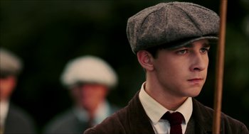 Movie still from “The Greatest Game Ever Played” (2005), directed by Bill Paxton – A young man wearing a hat and a tie; Close Up shot, Low angle