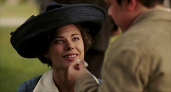 Movie still from “The Greatest Game Ever Played” (2005), directed by Bill Paxton – A woman wearing a black hat is smiling at a man; Close Up shot, Over the shoulder angle