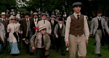 Movie still from “The Greatest Game Ever Played” (2005), directed by Bill Paxton – A group of men in suits and hats walking in a park; Medium shot, High angle