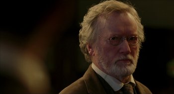 Movie still from “The Greatest Game Ever Played” (2005), directed by Bill Paxton – An older man with a beard and glasses; Close Up shot, Over the shoulder angle