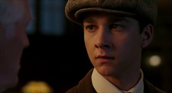 Movie still from “The Greatest Game Ever Played” (2005), directed by Bill Paxton – A young man wearing a hat looking at the camera; Close Up shot, Low angle