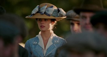 Movie still from “The Greatest Game Ever Played” (2005), directed by Bill Paxton – A woman wearing a hat with a bow on top of her head; Close Up shot, Over the shoulder angle