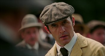 Movie still from “The Greatest Game Ever Played” (2005), directed by Bill Paxton – A person wearing a hat and a tie; Close Up shot, Low angle