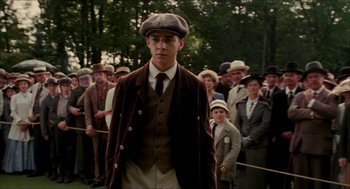 Movie still from “The Greatest Game Ever Played” (2005), directed by Bill Paxton – A group of people standing in a field with hats on; Medium shot, Low angle