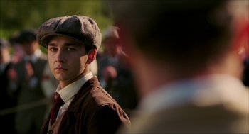 Movie still from “The Greatest Game Ever Played” (2005), directed by Bill Paxton – A young man wearing a hat and a brown jacket; Close Up shot, Over the shoulder angle