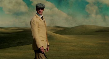 Movie still from “The Greatest Game Ever Played” (2005), directed by Bill Paxton – A man in a yellow jacket and hat holding a cane; Medium shot, Low angle