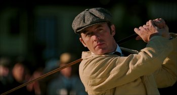Movie still from “The Greatest Game Ever Played” (2005), directed by Bill Paxton – A man holding a wooden stick in his hand; Close Up shot, Low angle