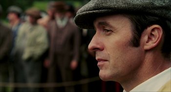 Movie still from “The Greatest Game Ever Played” (2005), directed by Bill Paxton – A person wearing a hat and looking to his left; Close Up shot, Low angle