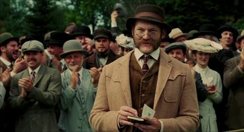 Movie still from “The Greatest Game Ever Played” (2005), directed by Bill Paxton – A man with a beard and mustache wearing a suit and a hat; Medium shot, Low angle