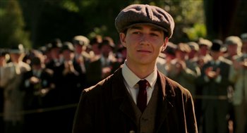 Movie still from “The Greatest Game Ever Played” (2005), directed by Bill Paxton – A young man in a suit and a hat is standing in front of a crowd; Close Up shot, Low angle