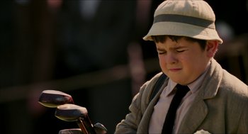Movie still from “The Greatest Game Ever Played” (2005), directed by Bill Paxton – A young boy wearing a hat and holding a golf club; Close Up shot, High angle