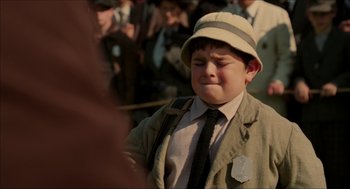 Movie still from “The Greatest Game Ever Played” (2005), directed by Bill Paxton – A young boy wearing a hat and a tie; Close Up shot, Over the shoulder angle