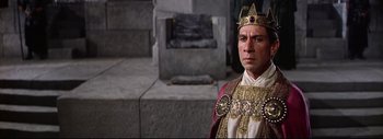Movie still from “The Greatest Story Ever Told” (1965), directed by David Lean – A man wearing a crown standing in front of a stone wall; Medium shot, High angle