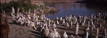 Movie still from “The Greatest Story Ever Told” (1965), directed by David Lean – A large group of people in white robes near a body of water; Extreme Wide shot, High angle