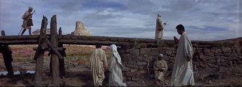 Movie still from “The Greatest Story Ever Told” (1965), directed by David Lean – A group of people standing next to each other on top of a stone wall; Wide shot, Low angle