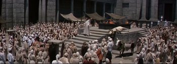 Movie still from “The Greatest Story Ever Told” (1965), directed by David Lean – A group of people sitting on steps in front of a building; Extreme Wide shot, High angle