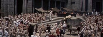 Movie still from “The Greatest Story Ever Told” (1965), directed by David Lean – A crowd of people sitting on steps in front of a building; Extreme Wide shot, High angle
