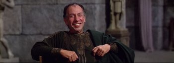 Movie still from “The Greatest Story Ever Told” (1965), directed by David Lean – A man smiling while wearing a green and gold outfit; Medium shot, Low angle