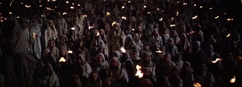 Movie still from “The Greatest Story Ever Told” (1965), directed by David Lean – A group of people are gathered in a crowd holding torches in their hands; Wide shot, High angle