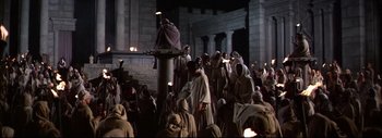 Movie still from “The Greatest Story Ever Told” (1965), directed by David Lean – A group of people gathered around a pillar in the dark; Wide shot, High angle